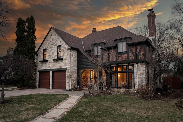 french provincial home featuring a chimney, a garage, a front yard, and stone siding