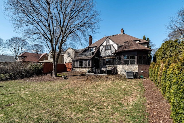 rear view of house with a sunroom, fence, and stone siding