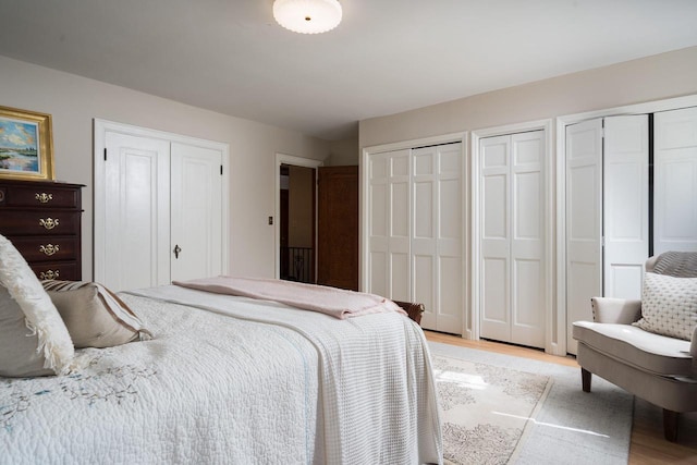 bedroom with multiple closets and light wood finished floors