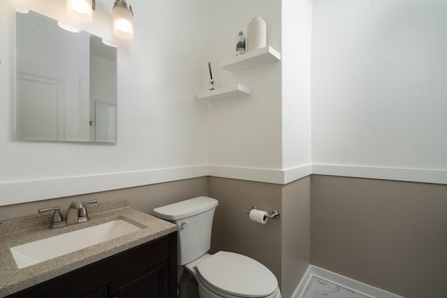 bathroom featuring toilet, marble finish floor, and vanity