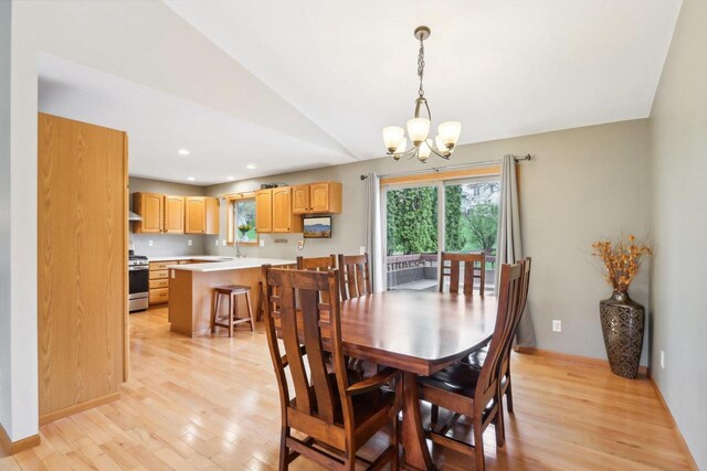 dining room with baseboards, a chandelier, lofted ceiling, and light wood-style floors