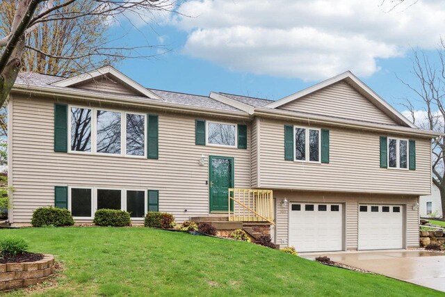 bi-level home with concrete driveway, a front yard, and a garage