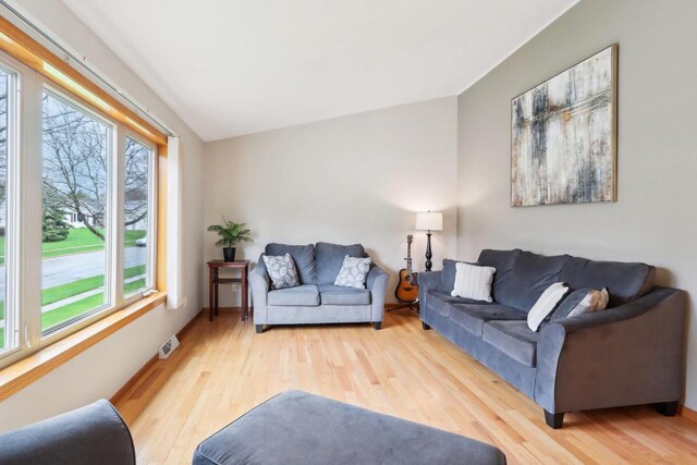 living area featuring visible vents, baseboards, and wood finished floors