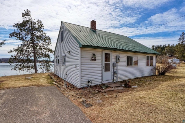 10439 W County Highway D, Exeland, WI 54835 - view of front facade featuring a water view, a front yard, metal roof, and a chimney