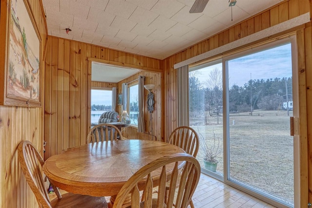 10439 W County Highway D, Exeland, WI 54835 - dining area featuring wood walls, ceiling fan, light wood-type flooring, and a healthy amount of sunlight