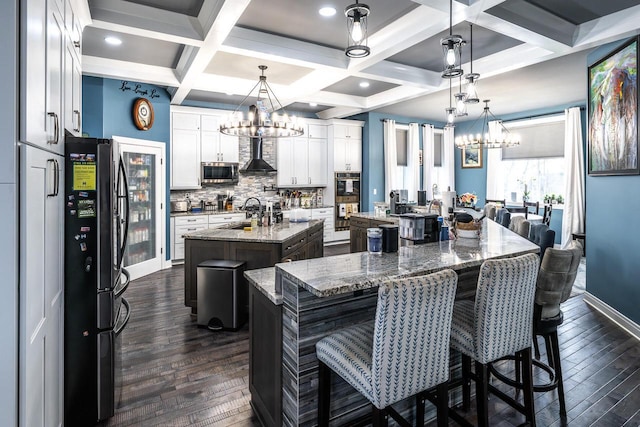 kitchen with coffered ceiling, a large island, an inviting chandelier, and stainless steel appliances