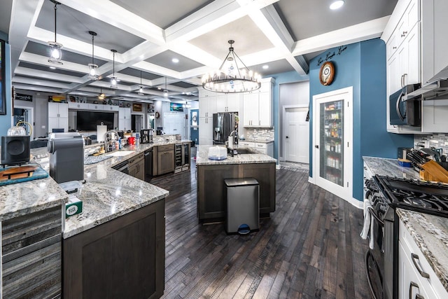 kitchen with dark wood-type flooring, appliances with stainless steel finishes, coffered ceiling, backsplash, and a spacious island