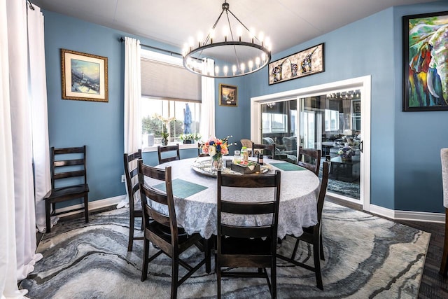 dining space with baseboards, a chandelier, and wood finished floors