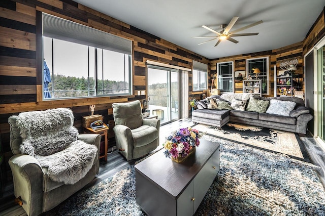 living area with wood walls, ceiling fan, and wood finished floors