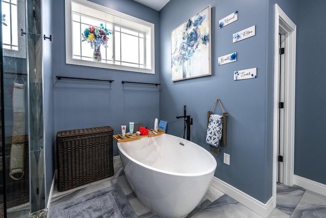 full bath with baseboards, marble finish floor, and a freestanding tub