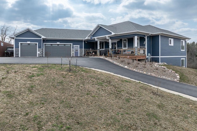 view of front of home featuring a garage, a porch, driveway, and stone siding