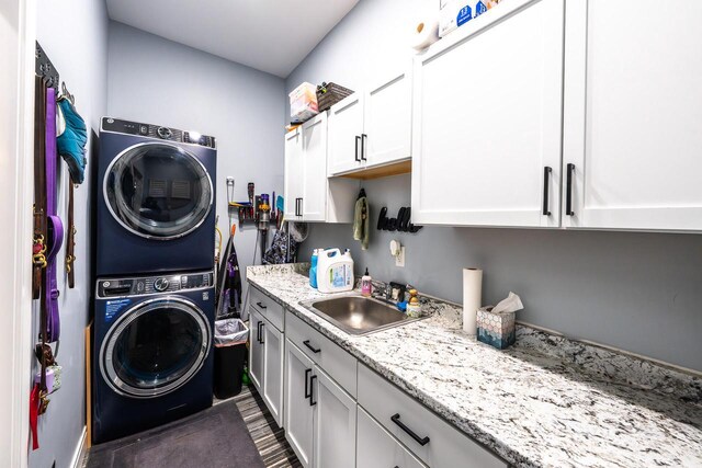 laundry room featuring stacked washing maching and dryer, a sink, and cabinet space