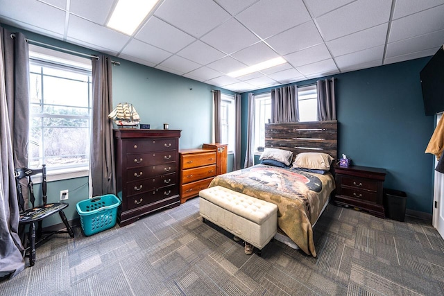 carpeted bedroom with baseboards and a drop ceiling
