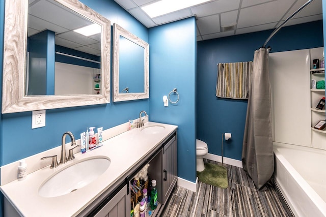 bathroom featuring toilet, a paneled ceiling, double vanity, and a sink