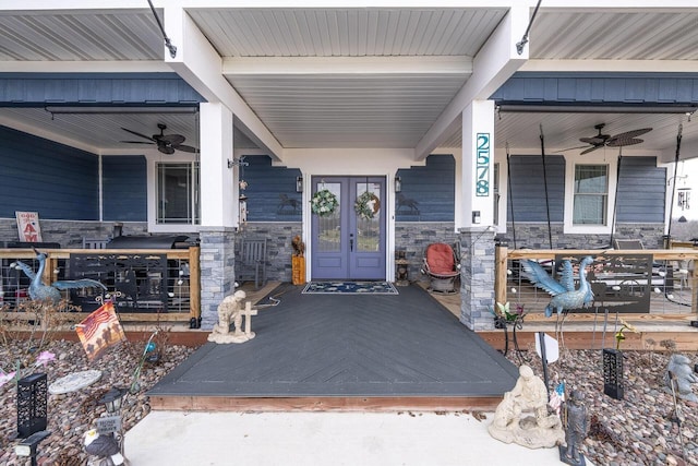 doorway to property featuring stone siding, a ceiling fan, and covered porch