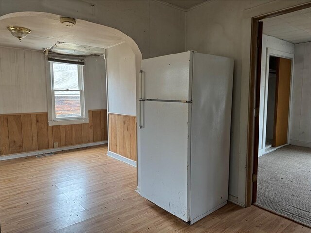 3168 W Howard St, Winter, WI 54896 - kitchen featuring wood walls, light wood finished floors, freestanding refrigerator, and a wainscoted wall