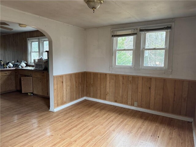 3168 W Howard St, Winter, WI 54896 - unfurnished dining area featuring light wood-style floors, wood walls, wainscoting, and arched walkways