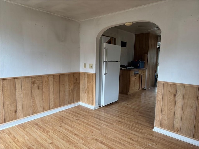3168 W Howard St, Winter, WI 54896 - spare room featuring arched walkways, wood walls, wainscoting, and light wood-type flooring