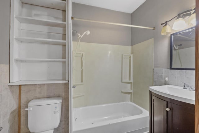 full bath featuring shower / washtub combination, vanity, toilet, wainscoting, and tile walls