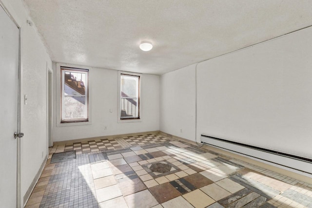 spare room with light tile patterned floors, baseboards, a textured ceiling, and baseboard heating