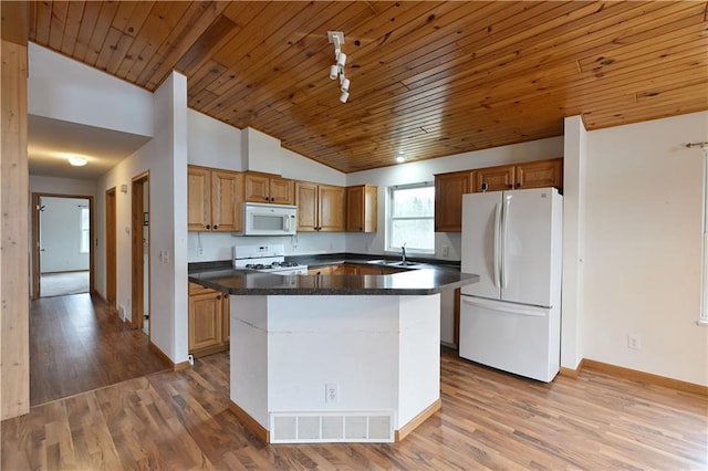 kitchen featuring white appliances, visible vents, dark countertops, a sink, and lofted ceiling