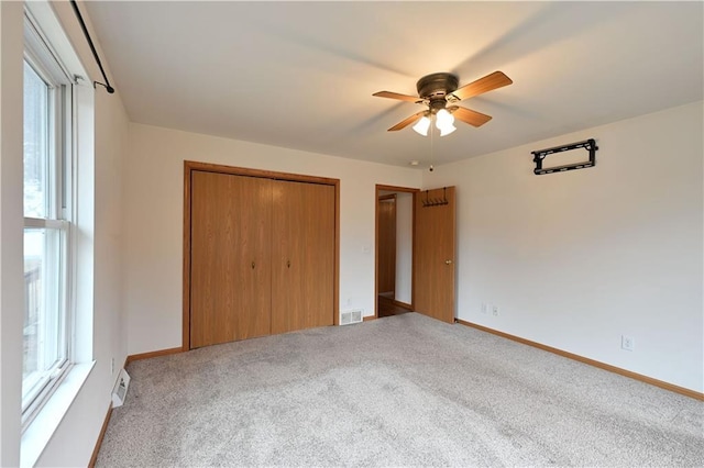 unfurnished bedroom featuring multiple windows, visible vents, and carpet floors