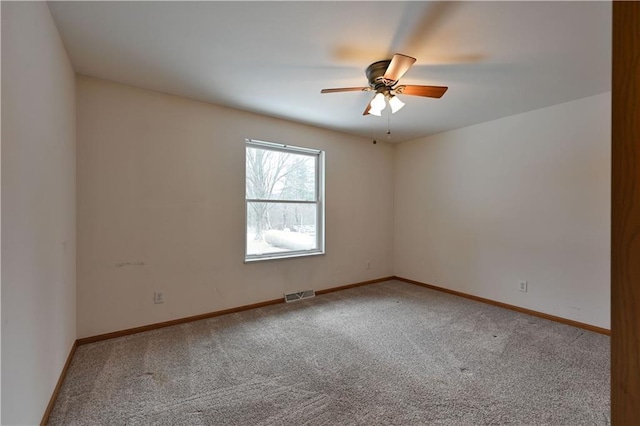 empty room with baseboards, carpet flooring, ceiling fan, and visible vents