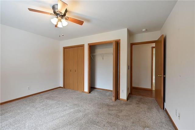 unfurnished bedroom featuring light carpet, baseboards, two closets, and a ceiling fan