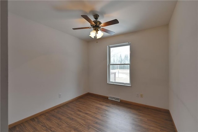 spare room with visible vents, baseboards, a ceiling fan, and dark wood finished floors