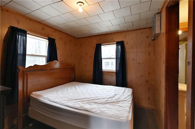 bedroom featuring wooden walls and multiple windows