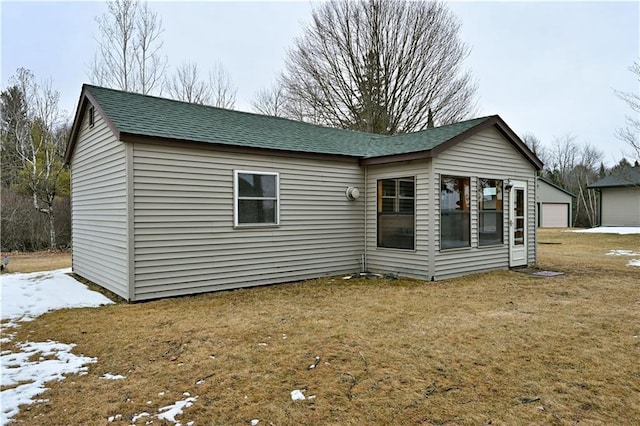 rear view of house with roof with shingles and a detached garage