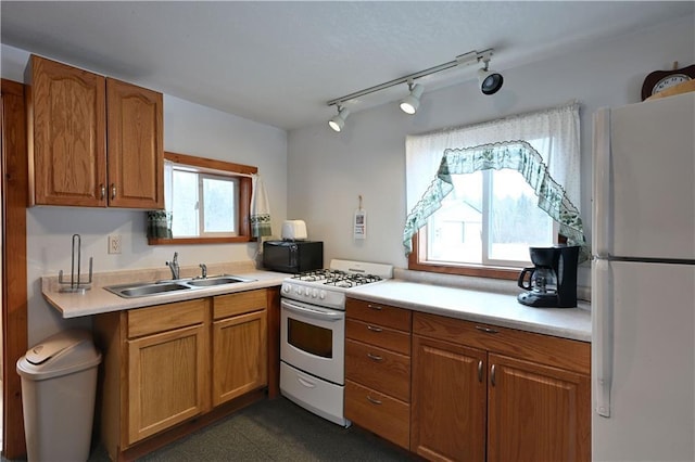 kitchen with light countertops, a sink, white appliances, and plenty of natural light