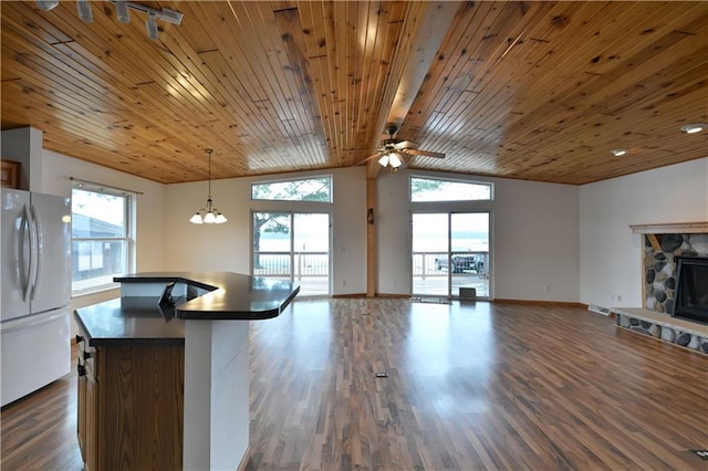 kitchen featuring open floor plan, dark countertops, freestanding refrigerator, a fireplace, and vaulted ceiling