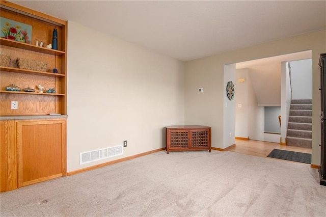 318 Meadow Lark Ln, Osceola, WI 54020 - unfurnished living room with light carpet, stairs, visible vents, and baseboards