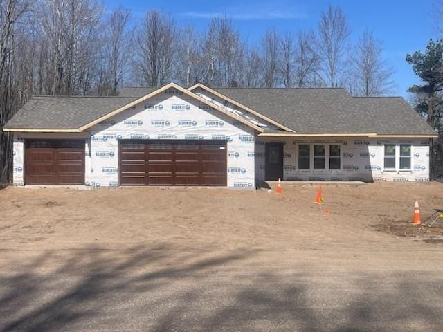 property under construction with dirt driveway and an attached garage