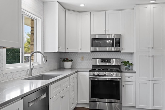 kitchen featuring white cabinets, a sink, light countertops, stainless steel appliances, and backsplash