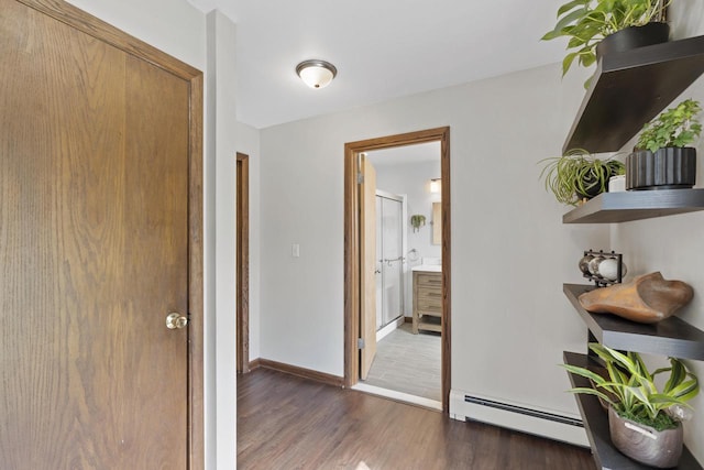hallway featuring baseboards, a baseboard radiator, and wood finished floors