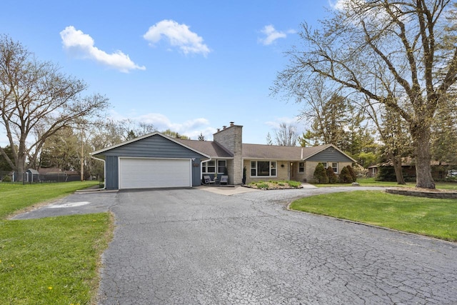 single story home featuring an attached garage, a chimney, a front yard, and aphalt driveway