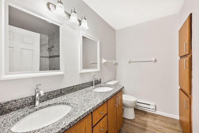 bathroom with toilet, wood finished floors, a baseboard heating unit, and a sink