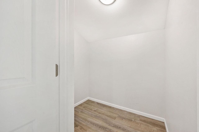 empty room with light wood-style floors, baseboards, and lofted ceiling