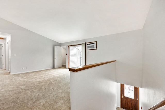 interior space featuring a wall unit AC, light colored carpet, baseboards, and lofted ceiling