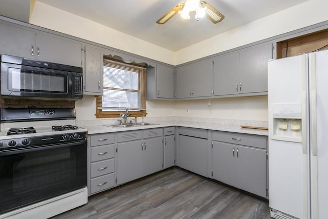 kitchen featuring white fridge with ice dispenser, black microwave, gas stove, a sink, and gray cabinetry