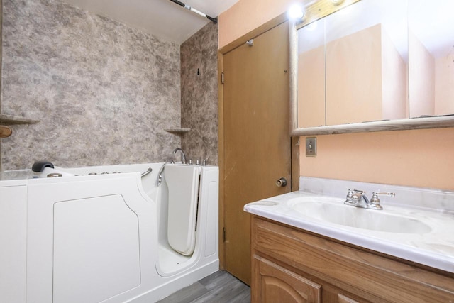bathroom with washer / clothes dryer, vanity, wood finished floors, and a washtub