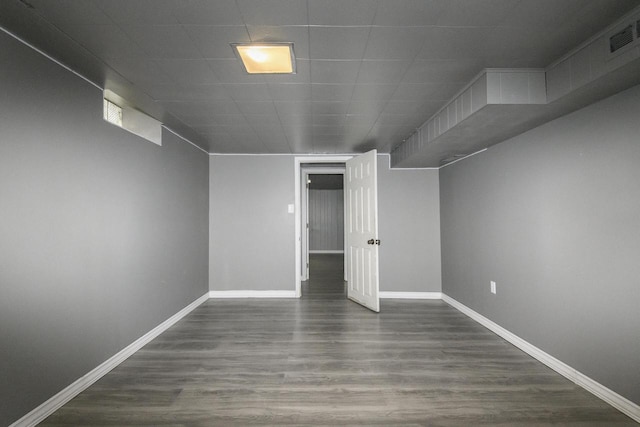finished basement with dark wood-style flooring, baseboards, and visible vents