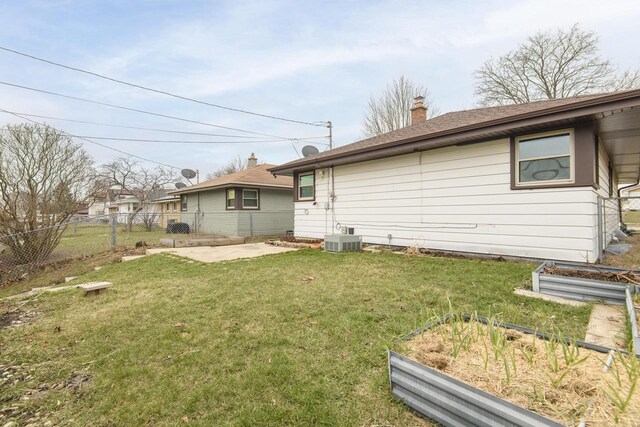 rear view of property with a vegetable garden, central AC, a yard, fence, and a chimney