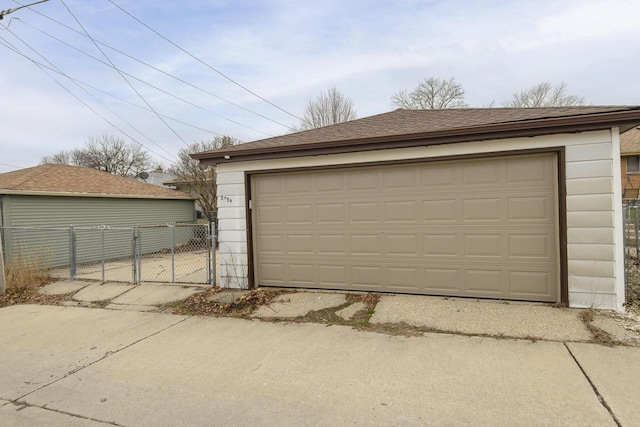 detached garage featuring fence and a gate