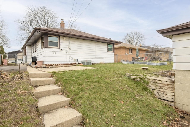 back of house with fence, cooling unit, a lawn, and a chimney