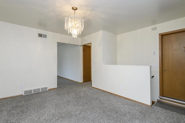 spare room featuring a chandelier, visible vents, baseboards, and carpet floors