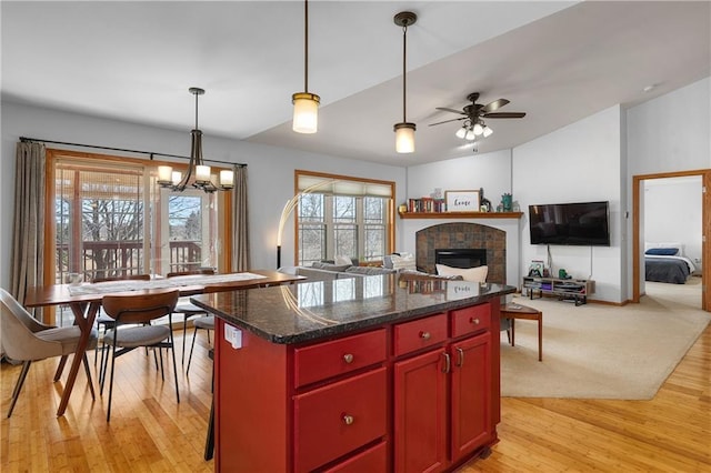 3943 Mill Run Rd, Eau Claire, WI 54703 - kitchen with a chandelier, light wood-style flooring, a tile fireplace, and red cabinets