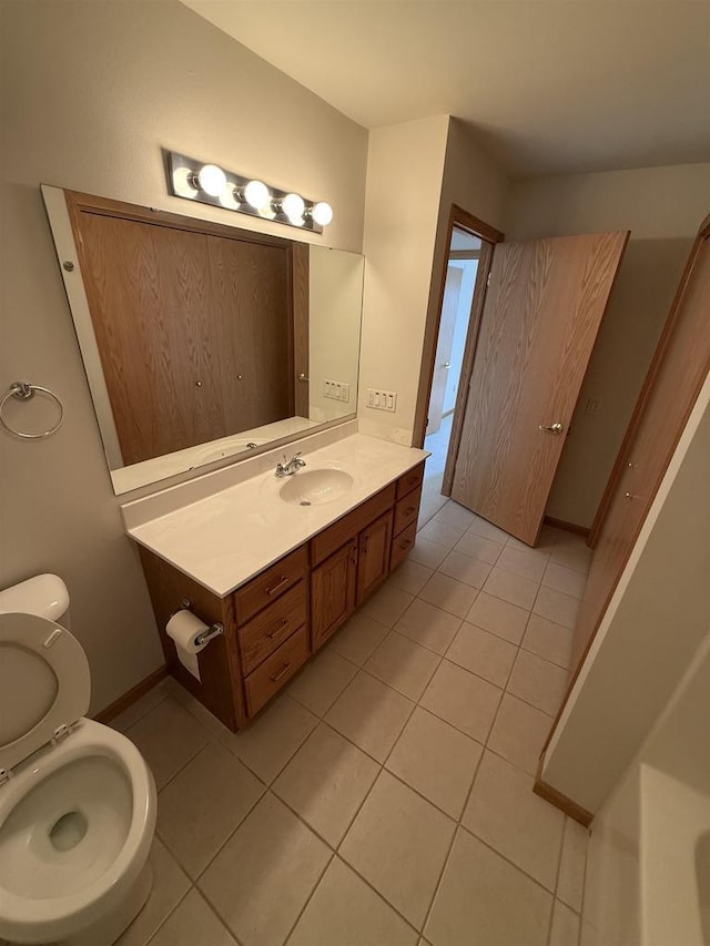 bathroom with tile patterned flooring, vanity, baseboards, and toilet
